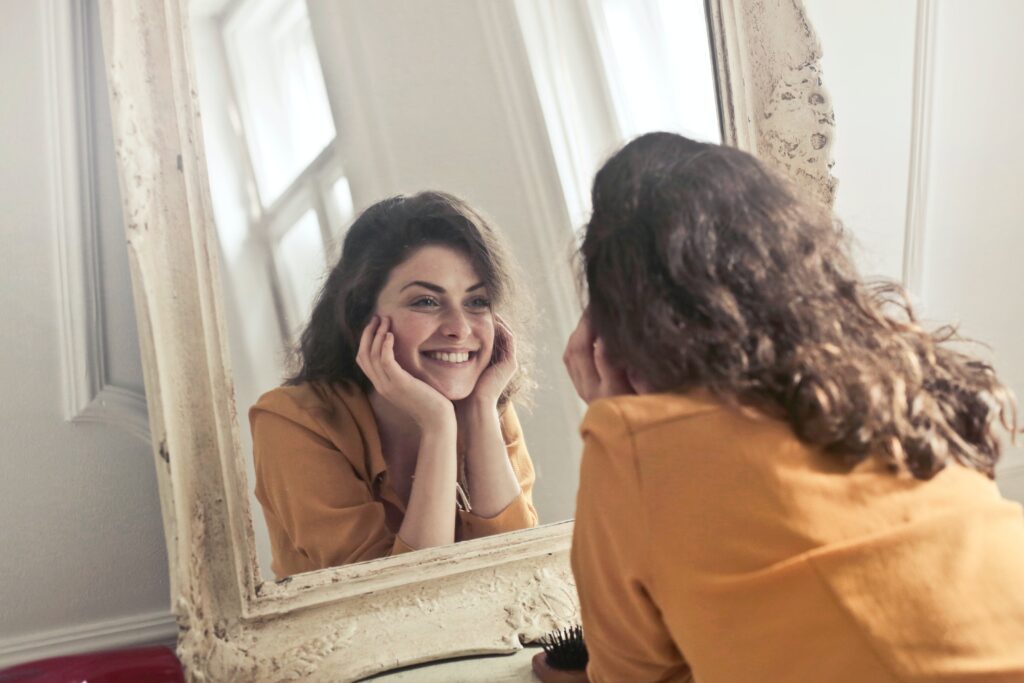 Image of a woman looking into the mirror and being happy